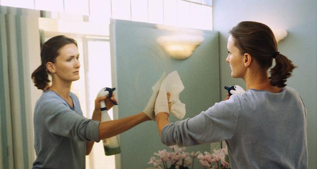 Woman cleaning a mirror