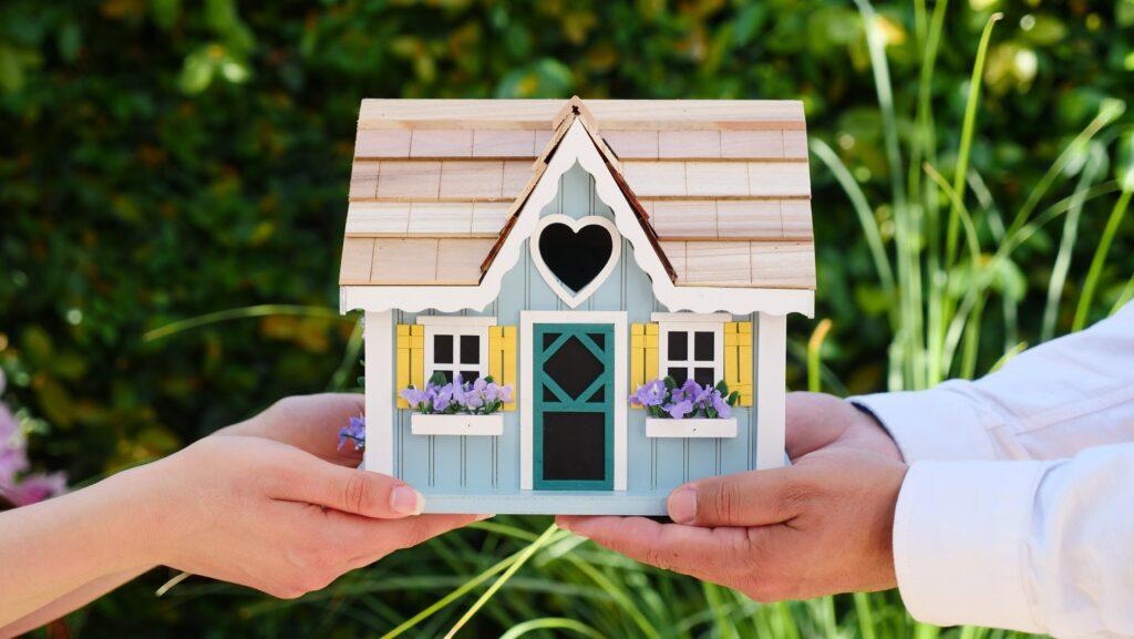 Two hands holding a small house